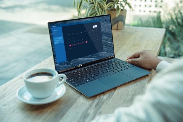 Laptop met agendaweergave op een houten tafel naast een kopje koffie
